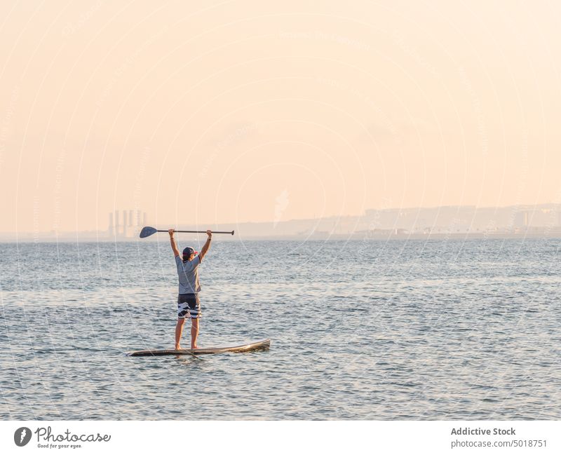 Mann mit Paddel auf Surfbrett auf hoher See Surfen MEER Meer Wasser aktiv Urlaub Sommer männlich Lifestyle extrem winken Abenteuer Erholung Athlet Sommerzeit