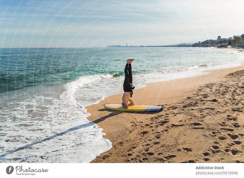 Surfer macht Handstand am Strand Mann Surfbrett Kopfstand MEER winken aktiv sportlich Übung Sommer Meer ohne Hemd männlich jung Sport Ufer Meeresufer Aktivität
