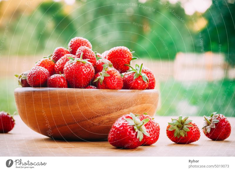 Hölzerne Schale gefüllt mit frischen reifen roten Erdbeeren auf Holztisch Natur schön natürlich hölzern geschmackvoll Ackerbau Sommer Picknick Garten
