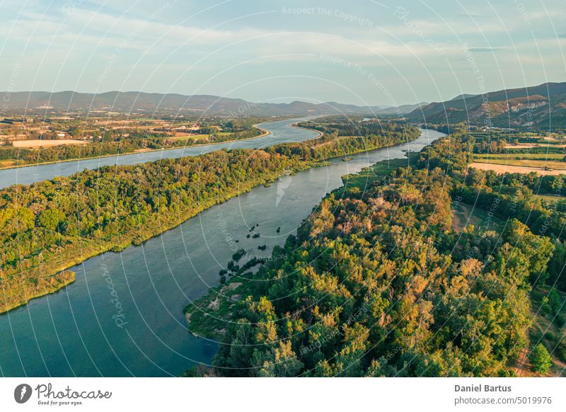 Luftaufnahme des Flusses Rhone in Südfrankreich. Eine natürlich geformte Insel in der Mitte des Flusses. Bewachsen mit Wäldern und Blick auf die umliegenden Berge