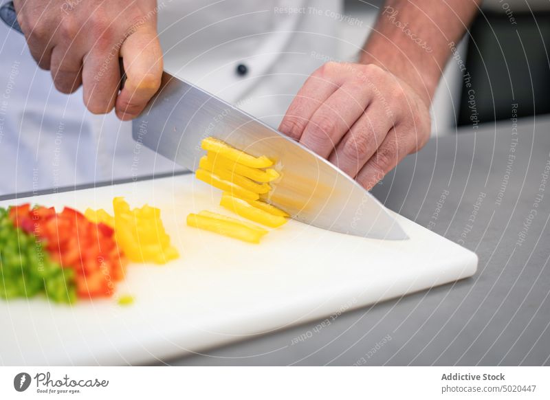 Profikoch schneidet Paprika Küchenchef Schneiden professionell grün Messer Schneidebrett Koch Mann Hand zerkleinernd Erwachsener Lebensmittel roh Gesundheit