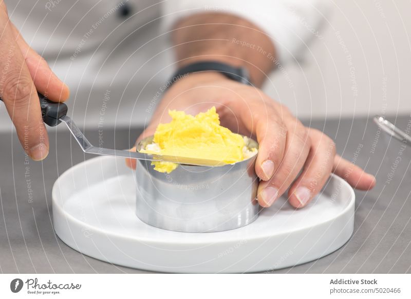 Unbekannter Koch, der Butter auf eine Backform auf einem Teller verteilt Mann Küchenchef Spachtel Utensil Aufstrich Prozess Tisch Bestandteil männlich Formular