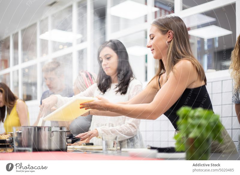 Positive Frauen kochen im Dampftopf beim Workshop Essen zubereiten Werkstatt Topf Hinzufügen Dämpfen Bestandteil positiv sorgsam lässig Schneidebrett Kochen