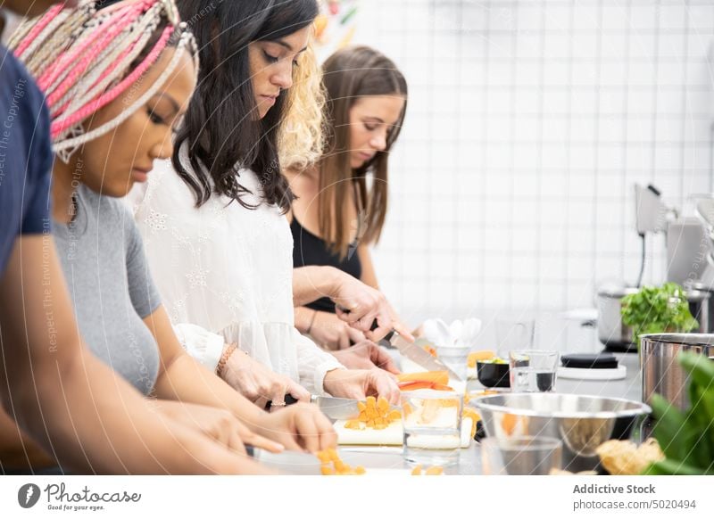 Multirassische Menschen lernen beim Kochworkshop, wie man Gemüse schneidet Essen zubereiten Werkstatt Lernen geschnitten achtsam fokussiert Schneiden Messer