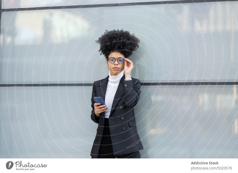 Schwarze Frau benutzt Smartphone in der Nähe eines Glasgebäudes Selfie Geschäftsfrau Großstadt Architekt Unternehmer Browsen elegant Anzug Talkrunde ethnisch