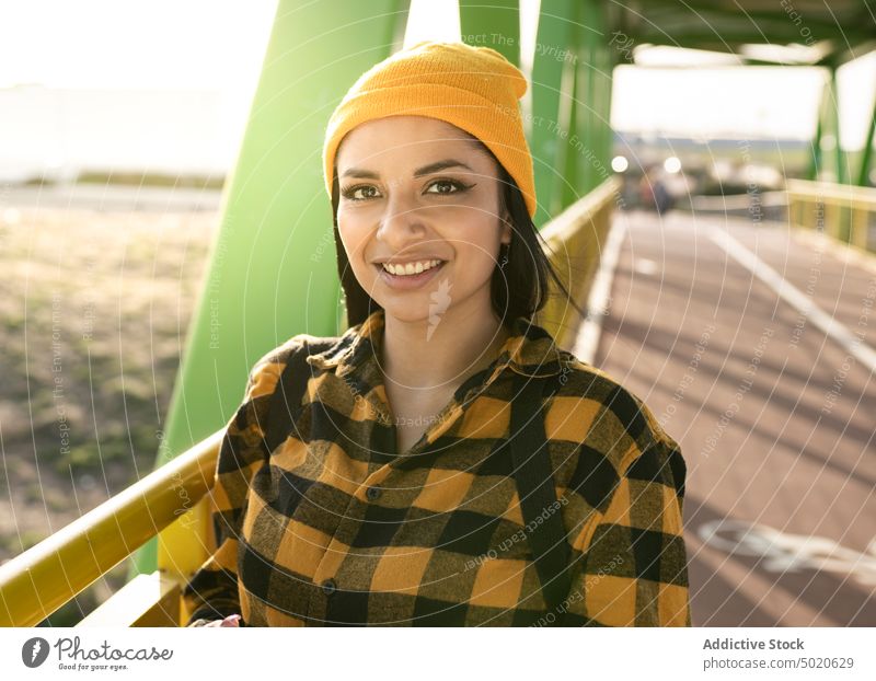 Glückliche junge lateinamerikanische Frau lächelt, während sie auf einer Brücke in der Stadt steht Lächeln Stil Spazierweg Optimist positiv Sonnenlicht genießen