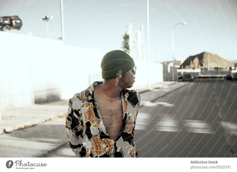 Junger schwarzer Mann auf einer Straße in der Stadt Stil Kinn reiben Wand Großstadt Außenseite Mode männlich modern Zeitgenosse Schatten selbstbewusst positiv