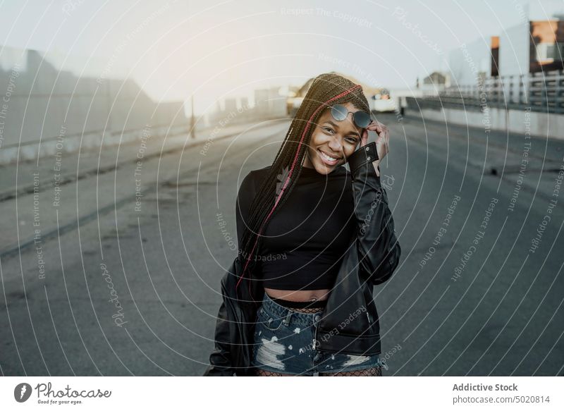 Lächelnde schwarze Frau auf der Straße Großstadt stylisch jung Lifestyle Freizeit trendy lässig Stadt urban Asphalt schäbig heiter Freude Dame Afroamerikaner
