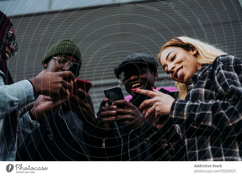Schwarze Freunde benutzen Smartphones auf der Straße benutzend Großstadt Zusammensein schwarz urban modern Mobile Telefon Männer Frauen Lifestyle Freizeit