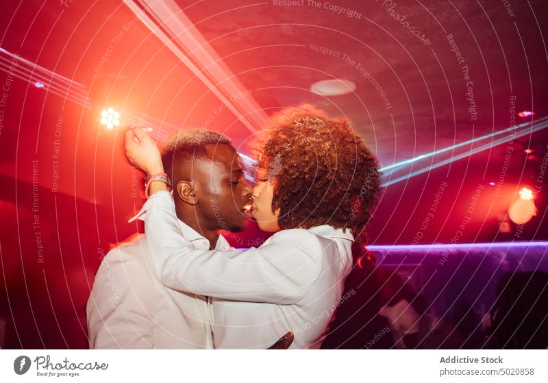 Schwarzes Paar küsst sich beim Tanzen Party Kuss Nachtleben Umarmung ethnisch neonfarbig leuchten unterhalten Mann Frau Lifestyle Freude Zusammensein feiern