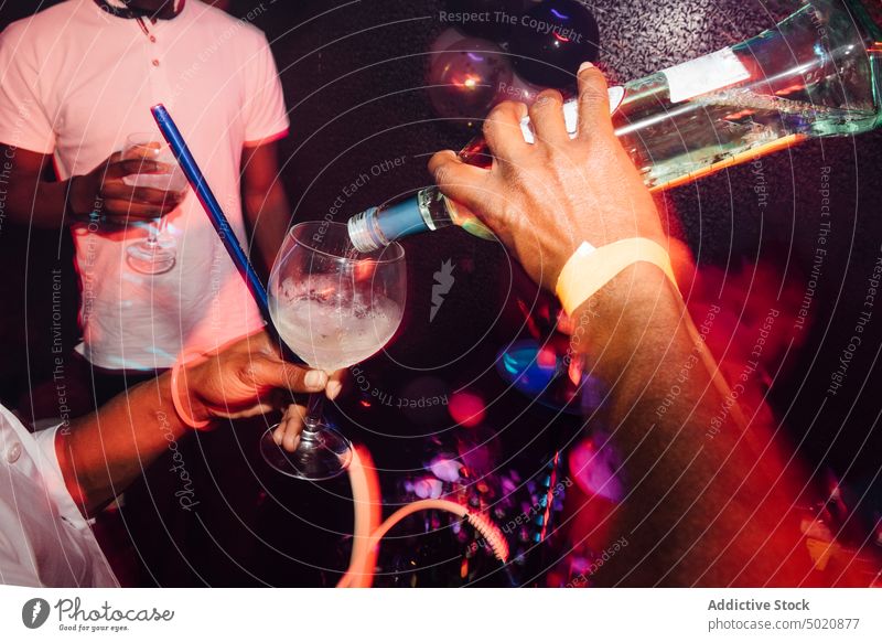 Ethnischer Barmann schenkt auf einer Party Alkohol aus trinken eingießen Nachtleben ethnisch Nachtclub Kelch Barkeeper Cocktail vorbereiten Getränk feiern