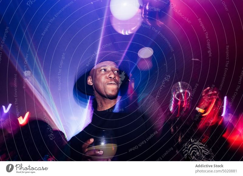 Schwarzer Mann trinkt Cocktail auf einer Party Nachtclub trinken Alkohol ethnisch farbenfroh leuchten neonfarbig männlich schlürfen Kelch Veranstaltung