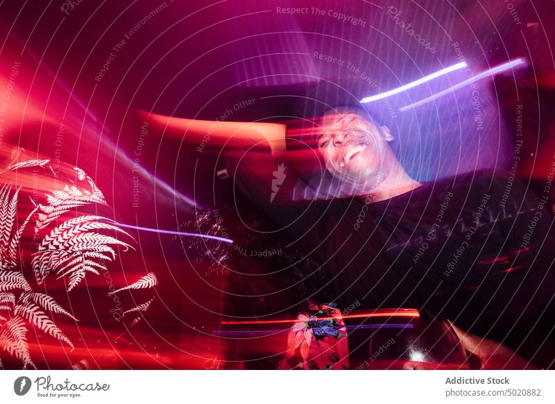 Schwarzer Mann trinkt Cocktail auf einer Party Nachtclub trinken Alkohol ethnisch farbenfroh leuchten neonfarbig männlich schlürfen Kelch Veranstaltung