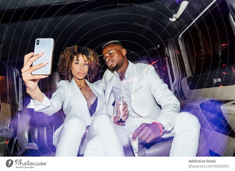 Afroamerikanisches Paar macht Selfie in Limousine Party Nachtleben Smartphone Champagne ausgefallen Zusammensein ethnisch Mitfahrgelegenheit Mann Frau
