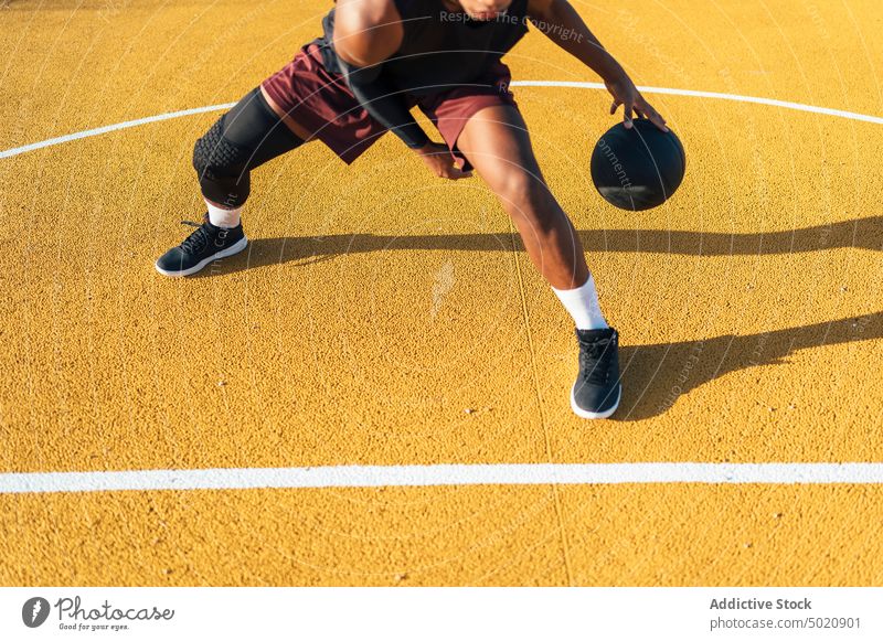 Aktiver schwarzer Sportler dribbelt Ball auf dem Spielplatz Dribbling Spieler tretend Spielen Sportbekleidung Aktivität Feld männlich kampfstark passen Athlet