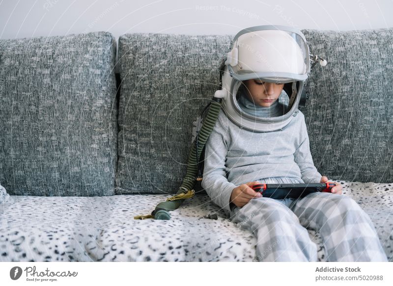 Niedliches Kind mit echter Astronautenuniform spielt mit einer Videospielkonsole Hintergrund Junge Kindheit Konzept Tracht Schaffung diy handgefertigt