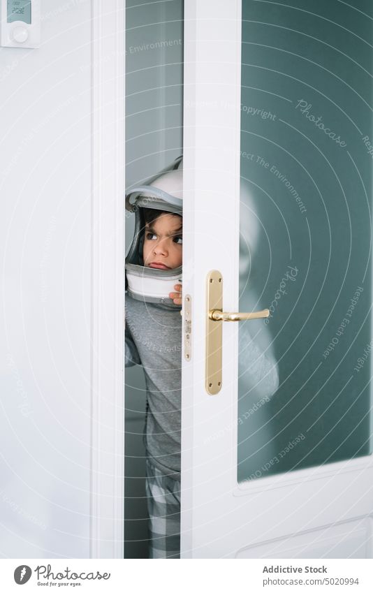 Niedliches Kind mit Helm schaut durch den Türspalt Astronaut Hintergrund Junge Kindheit Konzept Schaffung handgefertigt Heizung Thermostat Schutzhelm