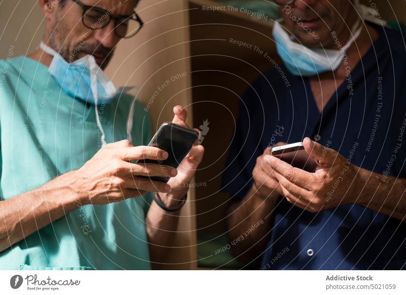 Chirurgen nutzen gemeinsam Smartphones Krankenhaus Büro benutzend Zusammensein Ärzte Klinik Gesundheitswesen Männer Team Uniform Medizin Technik & Technologie