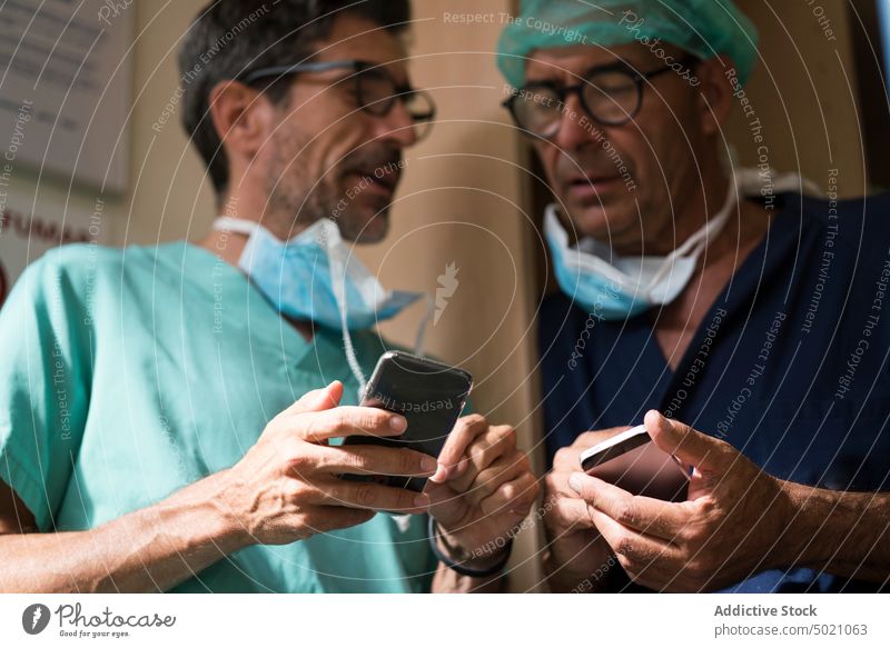 Chirurgen nutzen gemeinsam Smartphones Krankenhaus Büro benutzend Zusammensein Ärzte Klinik Gesundheitswesen Männer Team Uniform Medizin Technik & Technologie