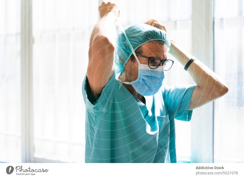 Chirurg setzt Maske auf Krankenhaus angezogen Mundschutz Vorbereitung Eingang Mann Erwachsener Arzt Medizin Gesundheitswesen Uniform bürstet Klinik