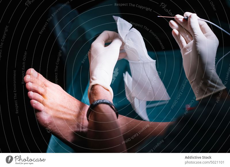 Abgelegte Hände beim Einführen der Nadel in die Füße des Patienten Chirurg einstecken Fuß geduldig Handschuhe Werkzeug Medizin Krankenhaus Gesundheit Behandlung