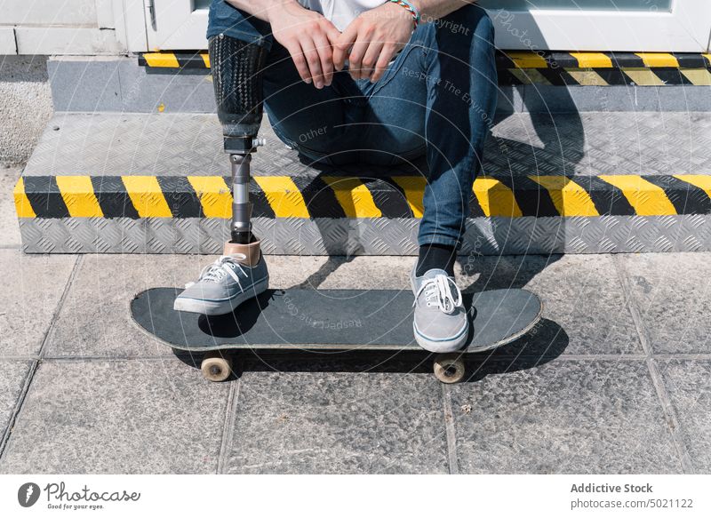 Schlittschuhläuferin mit Beinprothese auf einer Treppe sitzend Mann Skateboard künstlich Straße Großstadt jung urban männlich Prothesen modern sonnig tagsüber