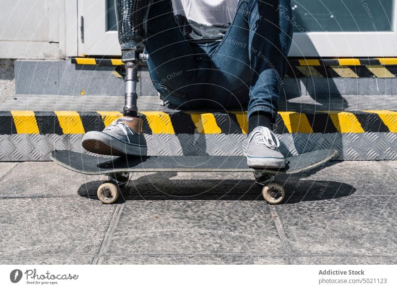 Schlittschuhläuferin mit Beinprothese auf einer Treppe sitzend Mann Skateboard künstlich Straße Großstadt jung urban männlich Prothesen modern sonnig tagsüber