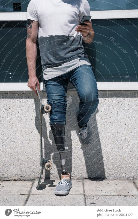 Crop Skater mit Beinprothese nutzt Smartphone Mann Skateboard künstlich Straße benutzend Großstadt jung urban männlich Prothesen modern Technik & Technologie