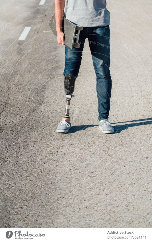 Anonymer junger Skater mit künstlichem Bein auf der Straße Skateboard Mann urban Großstadt im Freien Amputierte anonym Pause Browsen lässig Ernte tagsüber Gerät