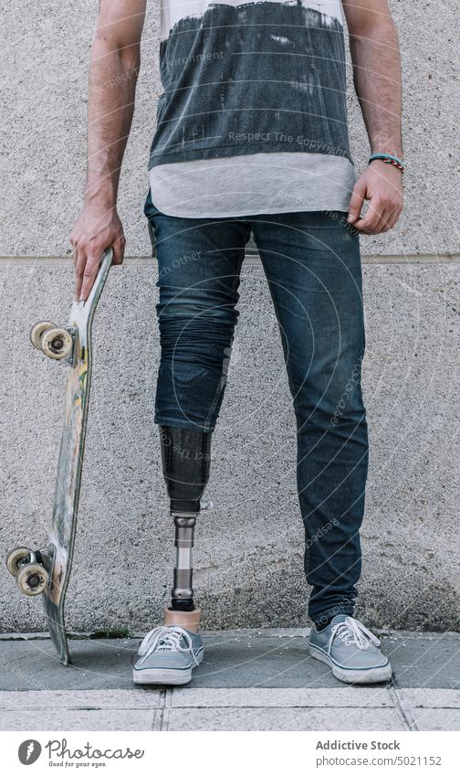 Anonymer junger Skater mit künstlichem Bein auf der Straße Mann Skateboard Motivation urban Kraft Lifestyle Stadt Straßenbelag Großstadt Wand Gebäude
