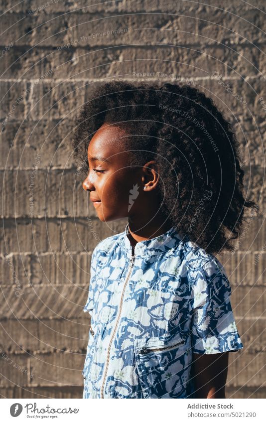 Lächelndes schwarzes Mädchen schaut weg in der Wand Schulmädchen heiter Glück Straße elementar Lifestyle klug Genuss Schule ethnisch Afroamerikaner Kindheit