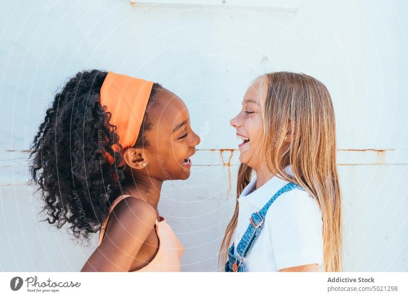 Fröhliches afroamerikanisches Mädchen mit bester Freundin, die in der Nähe einer weißen Wand Spaß haben Kinder Glück Lächeln Zusammensein vielfältig heiter