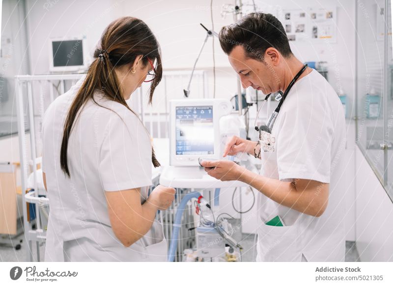 Ein Ärztepaar kontrolliert die Arbeit eines medizinischen Geräts im Krankenhaus Arzt Frau Paar Mann modern Steuerung Einstellung Behandlung Gesundheitswesen Kur
