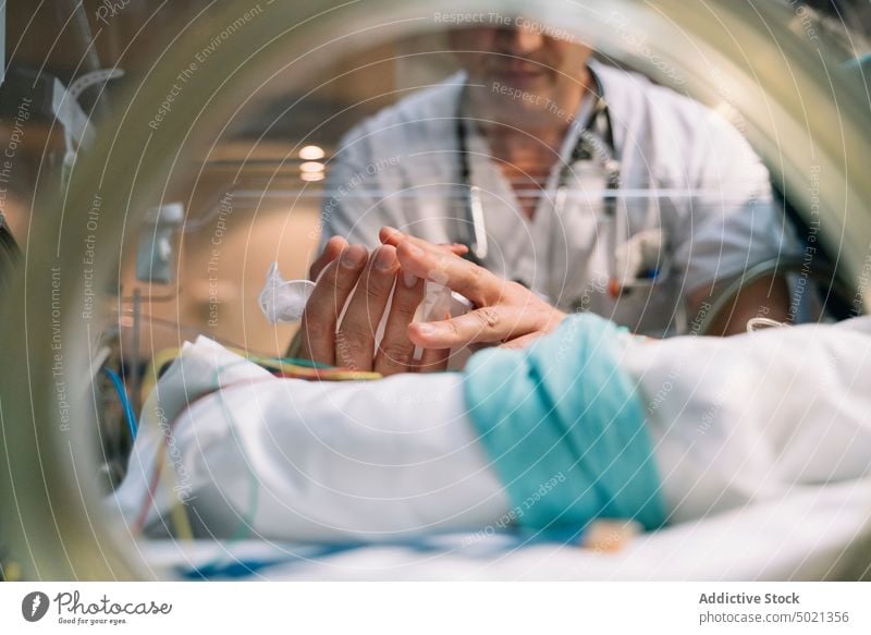Arzt kümmert sich um neugeborenes Baby im Inkubator Brutkasten medizinisch Kinderärztin Krankenhaus Behandlung Neonatologe Pflege Mann unschuldig