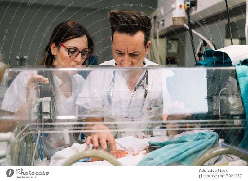 Ärzte kümmern sich um ein Neugeborenes im Inkubator Arzt neugeboren Brutkasten medizinisch Frau Mann Kinderärztin Baby Krankenhaus Behandlung Neonatologe Pflege