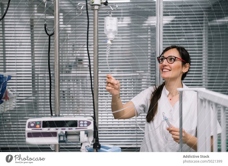 Lächelnder Arzt beim Einstellen der Tropfer auf der Station Krankenhaus medizinisch Gerät Rehabilitation Einstellung Behandlung Krankenpfleger Gesundheitswesen
