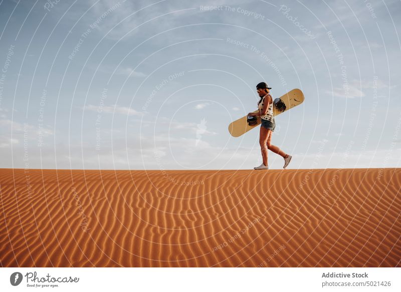 Junge Frau geht auf Sand und ist bereit für Sandboarding Sport extrem wüst Lifestyle Freizeit Spaß Urlaub reisen Feiertag Tourismus trocknen Düne Genuss