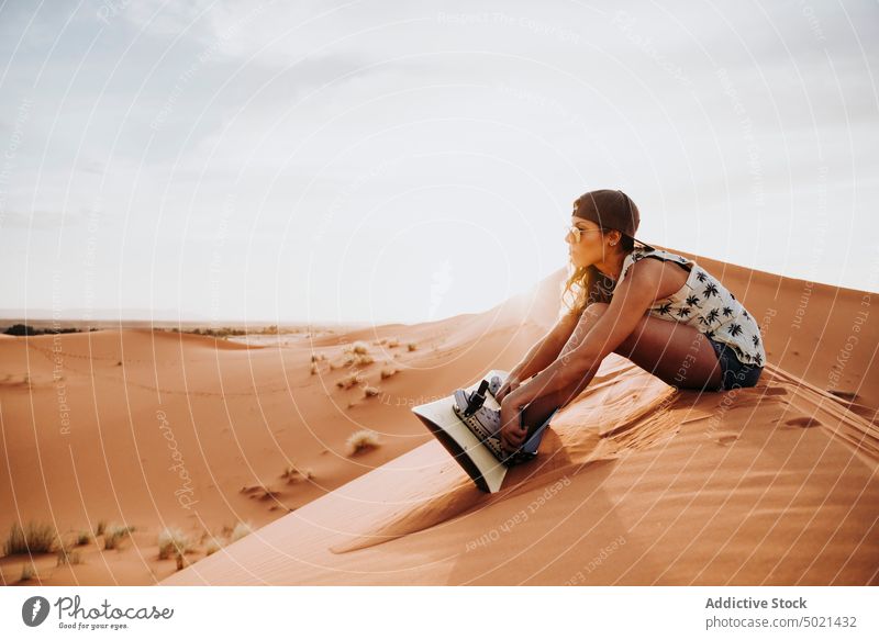 Junge Frau sitzt auf Sand, bereit zum Sandboarding Sport extrem wüst Lifestyle Freizeit Spaß Urlaub reisen Feiertag Tourismus trocknen Düne Genuss vorbereiten