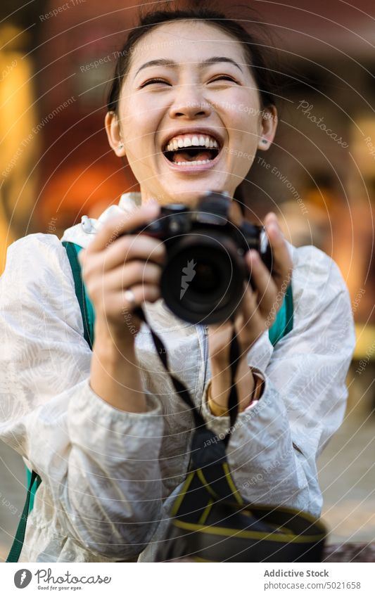 Glücklicher ethnischer Tourist mit Fotoapparat Frau fotografieren Lachen Straße Gedächtnis Indien asiatisch Augen geschlossen Fotograf lässig Ausflug aufgeregt