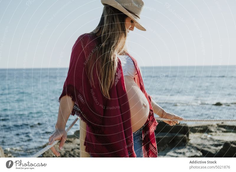 Schwangere Frau ruht sich am Meer aus schwanger ruhen MEER Küste Sommer Wochenende Urlaub Hut lässig Blauer Himmel Strand Bauch mütterlich tagsüber Resort Ufer