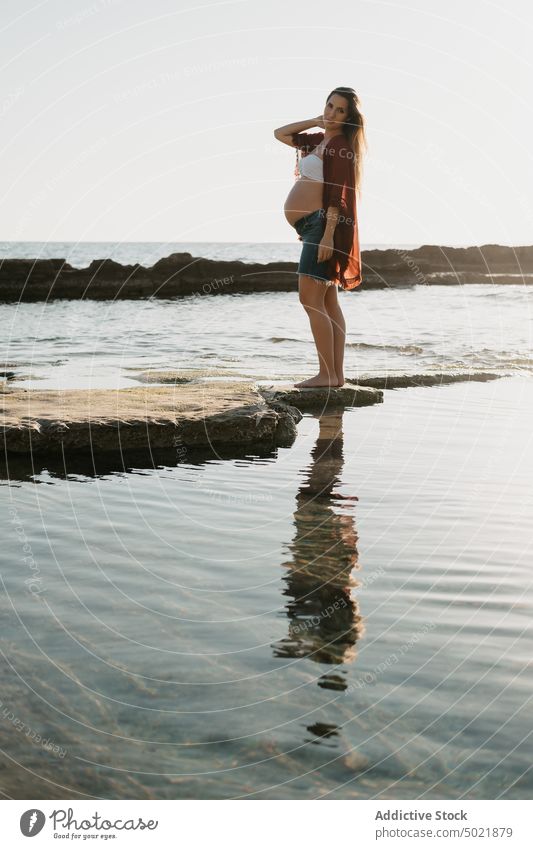 Schwangere Frau steht auf einem Stein am Meer schwanger MEER Ufer Morgen ruhen Wasser Sommer stehen Felsen Natur Küste sich[Akk] entspannen Sonnenaufgang
