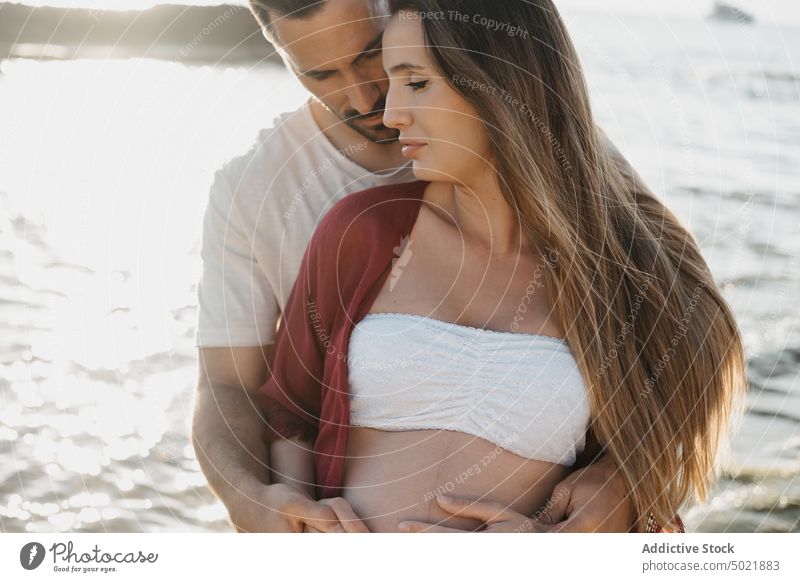 Schwangeres Paar am Meer stehend MEER Sonnenaufgang Schwangerschaft Umarmen Zusammensein Liebe Küste Partnerschaft Mann nachdenklich Frau Umarmung Ufer