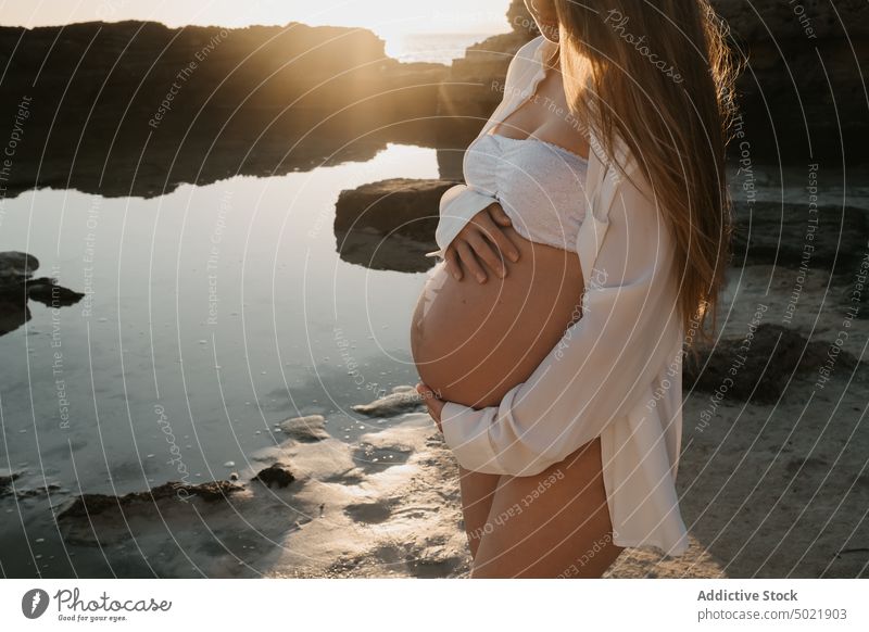 Anonyme schwangere Frau, die ihren Bauch in der Nähe von Meerwasser berührt MEER Sonnenaufgang ruhen Natur berühren Sommer Ufer Liebe Wasser Windstille