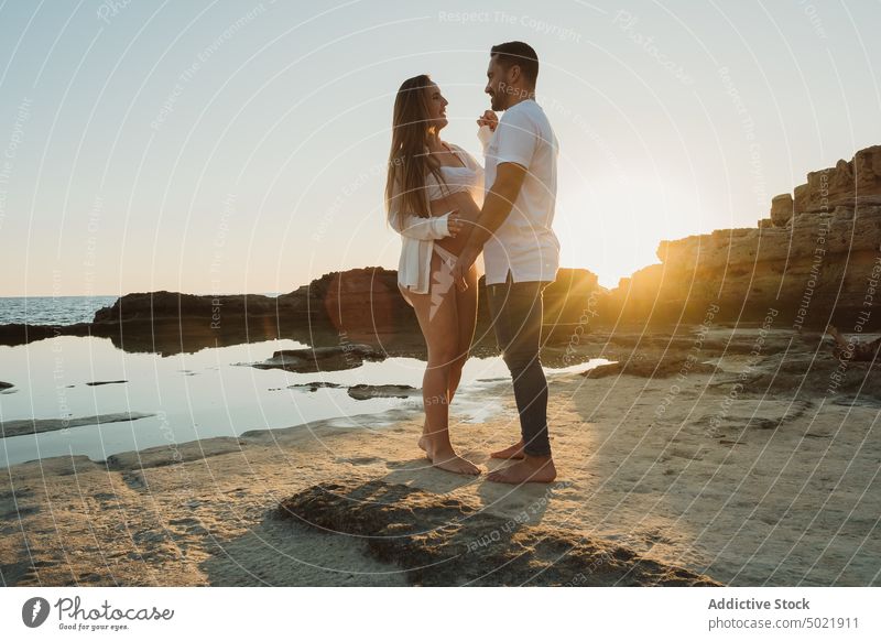 Schwangere Paar stehen in der Nähe Meer bei Sonnenaufgang MEER Schwangerschaft Zusammensein Liebe Küste Partnerschaft Händchenhalten Mann Frau Ufer schwanger