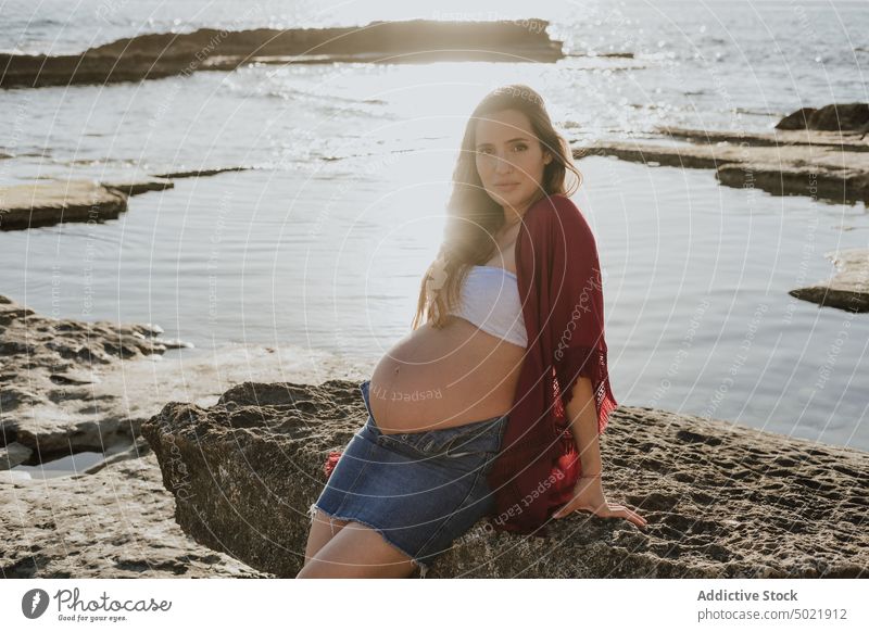 Schwangere Frau lehnt an einem Stein am Meer schwanger MEER Ufer fettarm Morgen ruhen Wasser Sommer Felsen Natur Küste sich[Akk] entspannen Sonnenaufgang
