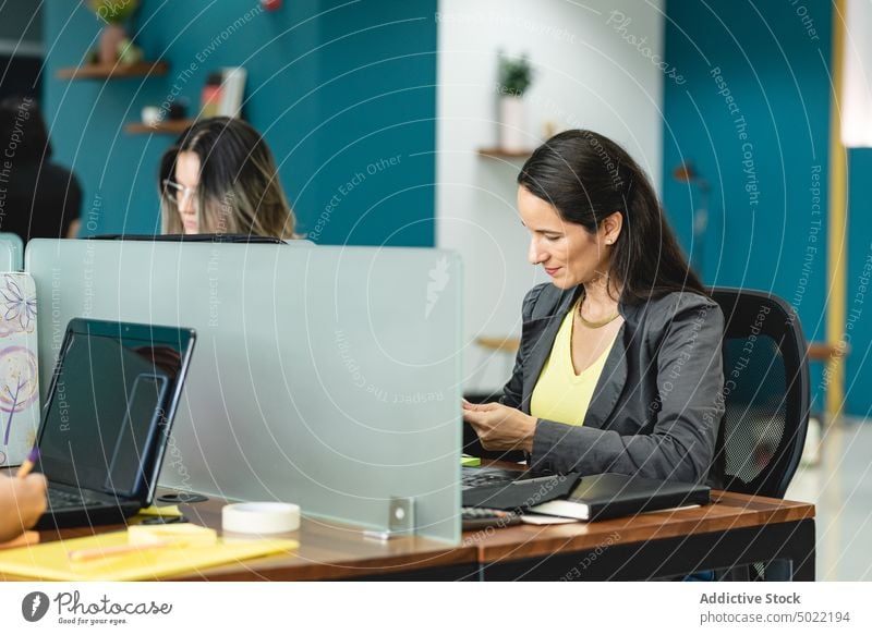 Konzentrierte ethnische Frau sitzt am Tisch mit Laptop während der Arbeit im Büro Unternehmer Projekt benutzend beschäftigt Konzentration sitzen hispanisch