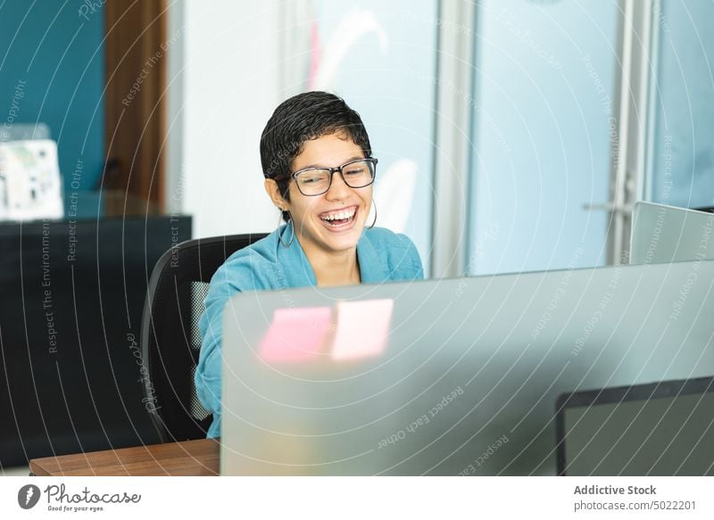 Glückliche ethnische Frau sitzt am Tisch mit Laptop während der Arbeit im Büro heiter Unternehmer benutzend Lachen positiv Job hispanisch Costa Rica amerika