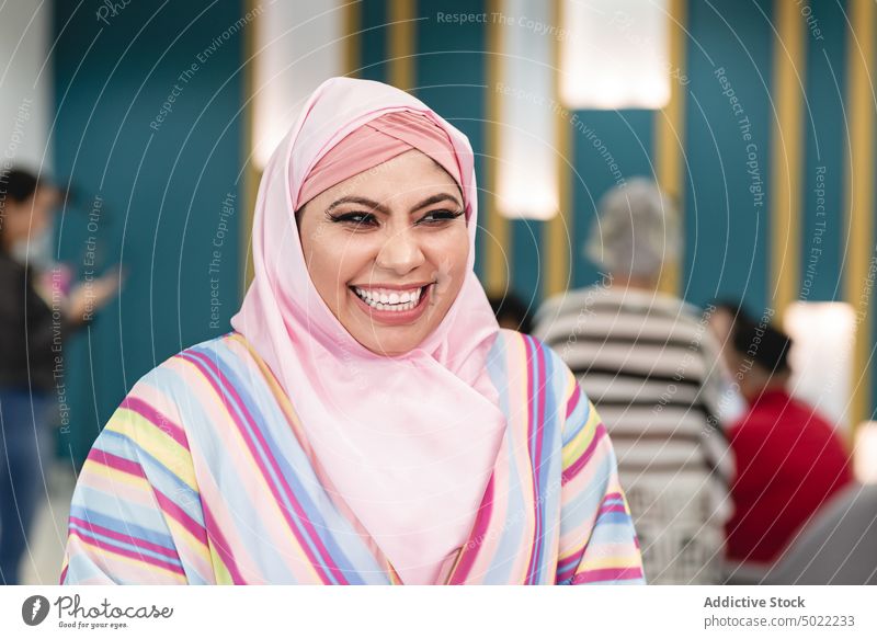 Muslimische Frau in modernem Arbeitsraum stehend positiv heiter Lächeln benutzend Apparatur Job Arbeitsbereich muslimisch Optimist Beruf Arbeitsplatz ethnisch