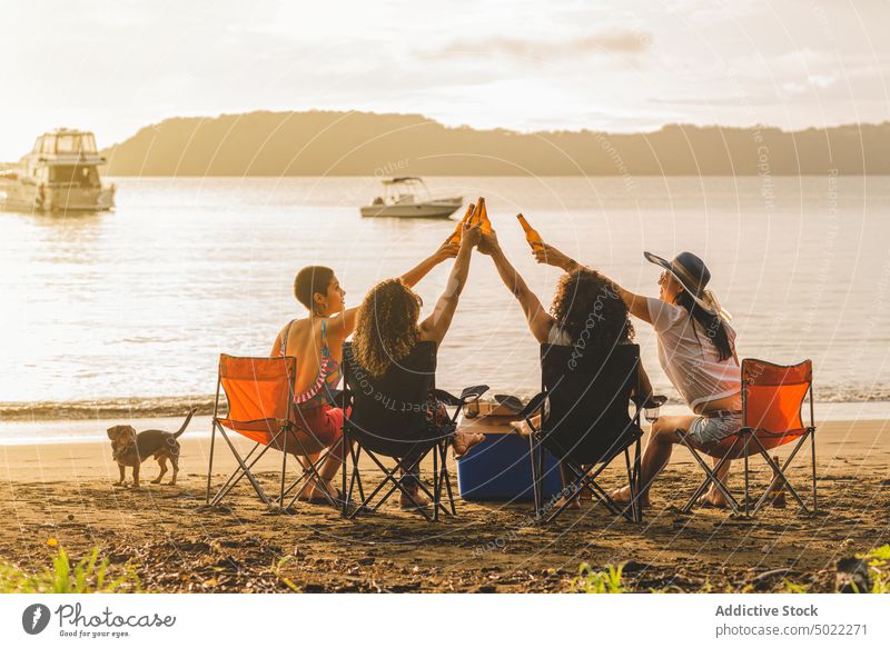 Junge Leute mit Bier bei einem Sommerpicknick am Strand Freund Klirren Flasche heiter sich[Akk] sammeln Treffpunkt Zusammensein Glück Menschengruppe jung