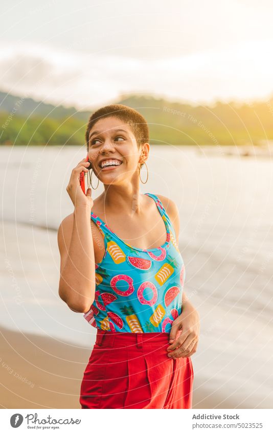 Glückliche ethnische Frau, die am Strand mit ihrem Smartphone spricht Sommer MEER Telefon Kommunizieren reden jung Lateinamerikaner Mobile Lächeln Kurze Haare